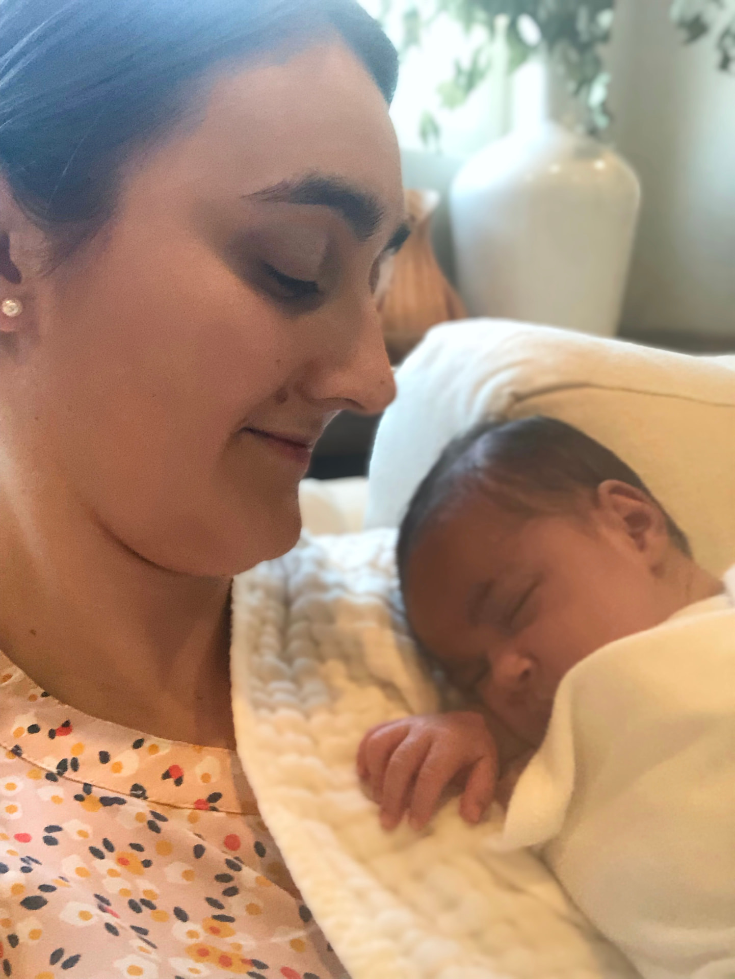 Nora holding a sleeping newborn close in soft natural light